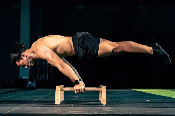 Strong-man-balancing-in-full-planche-on-wooden-parallettes-during-calisthenics-workout